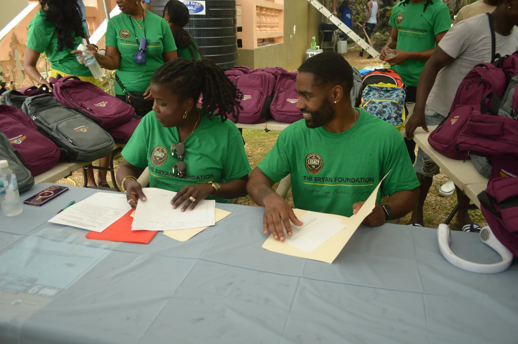 Volunteers registering children beside rows of backpacks